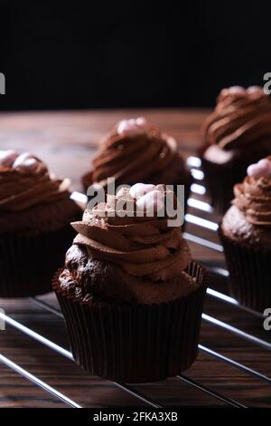 Délicieux cupcakes au chocolat noir, garniture en coeur de sucre, table texturée en bois. Boulangerie cacao, grille rustique étagère café-restaurant hippster table Banque D'Images