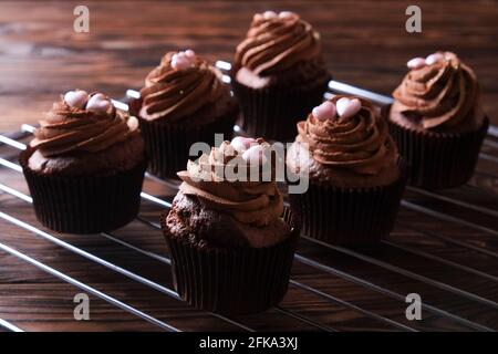 Délicieux cupcakes au chocolat noir, garniture en coeur de sucre, table texturée en bois. Boulangerie cacao, grille rustique étagère café-restaurant hippster table Banque D'Images