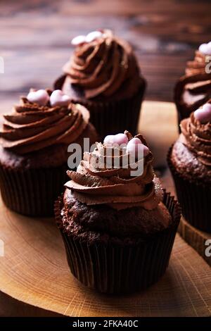 Délicieux cupcakes au chocolat noir, garniture en coeur de sucre, table texturée en bois. Boulangerie au cacao, café rustique en tranches d'arbre en bois, tabl de l'hippopotame Banque D'Images
