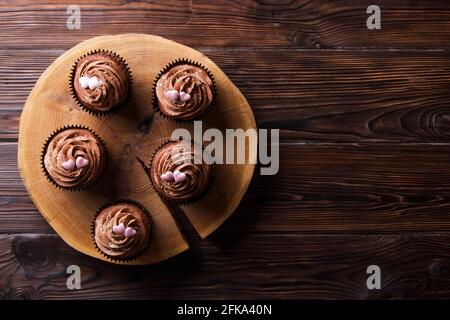Délicieux cupcakes au chocolat noir, garniture en coeur de sucre, table texturée en bois. Boulangerie au cacao, café rustique en tranches d'arbre en bois, tabl de l'hippopotame Banque D'Images