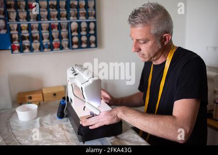 un tailleur travaillant avec sa machine à coudre dans sa petite préparation de l'atelier Banque D'Images