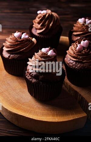 Délicieux cupcakes au chocolat noir, garniture en coeur de sucre, table texturée en bois. Boulangerie au cacao, café rustique en tranches d'arbre en bois, tabl de l'hippopotame Banque D'Images
