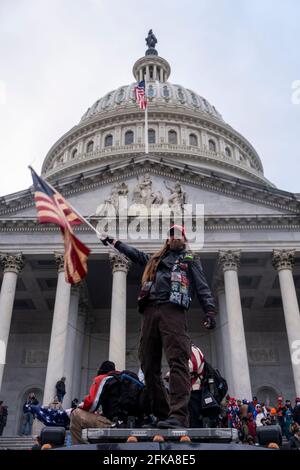 Washington DC, États-Unis. 6 janvier 2021. Un homme fait un drapeau devant le Capitole lors de la tempête du bâtiment par les partisans de Trump. Banque D'Images