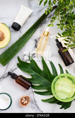 Une belle composition avec de l'huile, du savon, de l'avocat et des noix. Bouteilles avec produits cosmétiques spa sur fond de palmier, vue du dessus. Salon de beauté procedu Banque D'Images