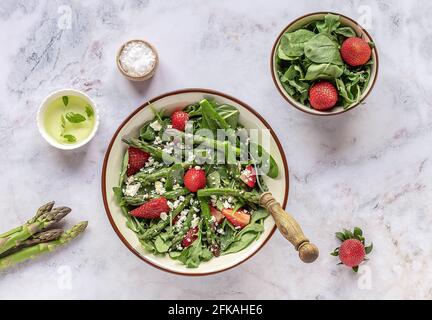 Une salade saine et délicieuse à base de fraises fraîches, d'asperges vertes, de feta et de feuilles de légumes. Banque D'Images