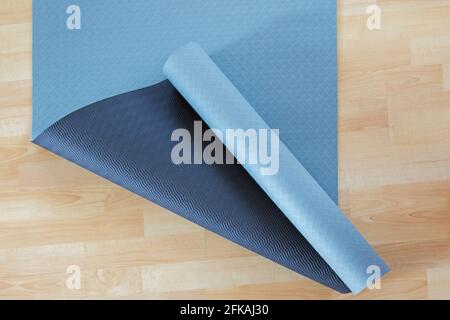 Épais antidérapant bleu et noir exercice yoga ou Tapis de méditation en PVC sur parquet laminé jaune Banque D'Images