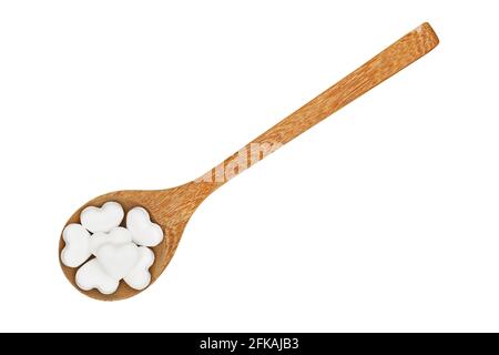 Une cuillère en bois pleine de pilules de bonbons en forme de coeur isolé sur fond blanc Banque D'Images