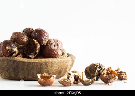 Noix de savon dans un bol en bois sur fond blanc; mode de vie écologique; durable; biologique Banque D'Images