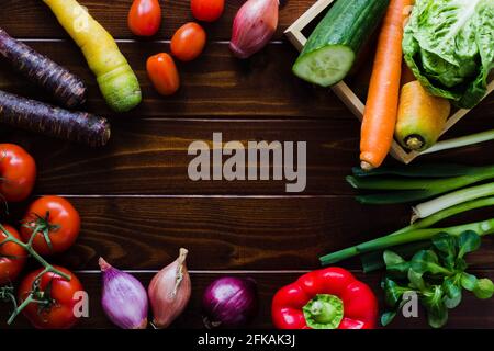 Différents types de légumes frais, mûrs et colorés dans un cercle sur le bois sombre; récolte Banque D'Images