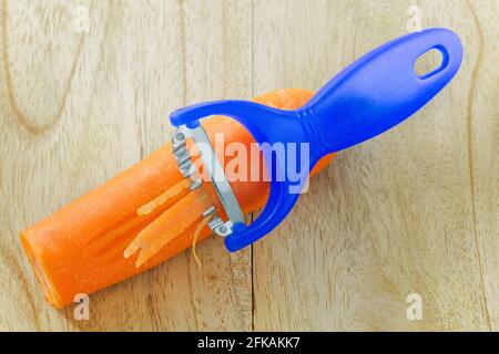 Outil de trancheuse à couteau en acier inoxydable pour râper les carottes en bleu un fond en bois Banque D'Images