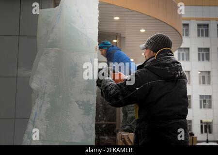 Le sculpteur coupe une figure hors de la glace par une tronçonneuse pour Noël Banque D'Images