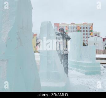 Le sculpteur coupe une figure hors de la glace par une tronçonneuse pour Noël Banque D'Images