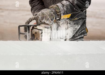 Le sculpteur coupe une figure hors de la glace par une tronçonneuse pour Noël Banque D'Images