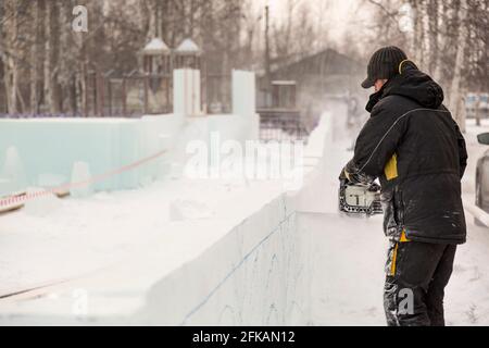 Le sculpteur coupe une figure hors de la glace par une tronçonneuse pour Noël Banque D'Images