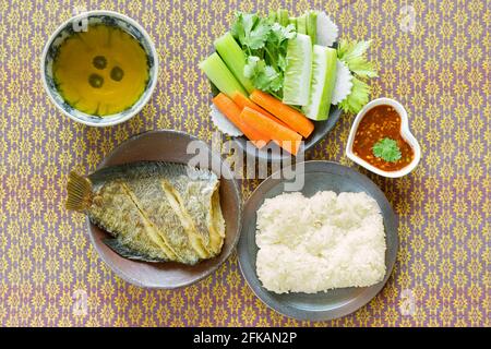 Poisson frit à la feuille de Gounrami, riz collant, légume frais et tisane sur fond de tissu Banque D'Images