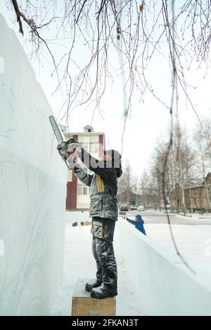 Le sculpteur coupe une figure hors de la glace par une tronçonneuse pour Noël Banque D'Images
