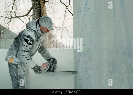 Le sculpteur coupe une figure hors de la glace par une tronçonneuse pour Noël Banque D'Images