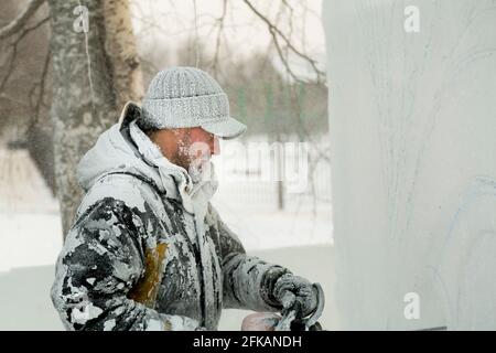 Le sculpteur coupe une figure hors de la glace par une tronçonneuse pour Noël Banque D'Images