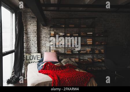 ce studio de luxe dispose d''un aménagement gratuit dans le style loft aux couleurs sombres. Bibliothèque élégante avec lit Banque D'Images