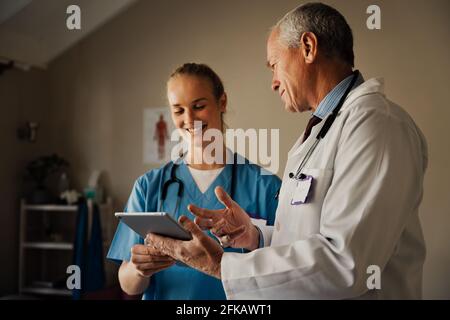 Les médecins hommes et femmes souriant regardant des résultats positifs sur la tablette numérique. Banque D'Images