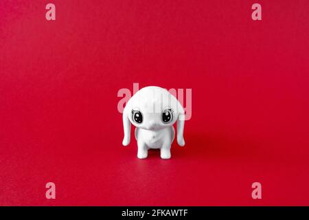Jouet pour chiot blanc sur fond rouge. Concept minimaliste, vue avant Banque D'Images
