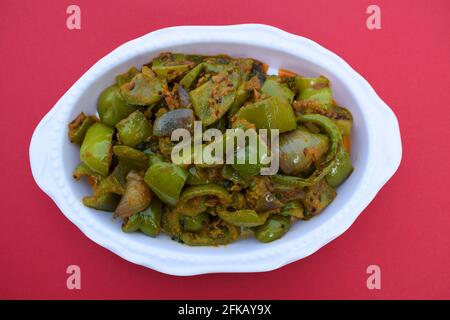 Délicieux cari au poivron vert ou au poivron vert. Remuez avec des oignons sautés sabaji asiatique indien avec du masala. Sur fond rouge, l'image de la nourriture est un espace de copie de Banque D'Images