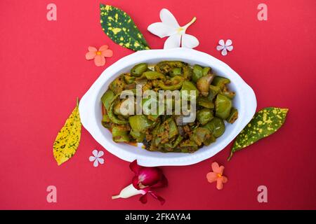 Délicieux cari au poivron vert ou au poivron vert. Remuez avec des oignons sautés sabaji asiatique indien avec du masala. Sur fond rouge, l'image de la nourriture est un espace de copie de Banque D'Images