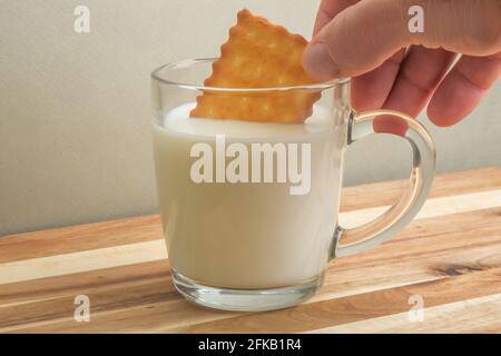 un homme plonge un cookie dans un verre de lait. Banque D'Images
