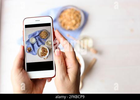 Jeune femme blogueur de nourriture prend photo pour le blog, photo de bol avec yaourt grec granola maison, noix mélangées, amande, noix de cajou, noisette. Végétaria saine Banque D'Images