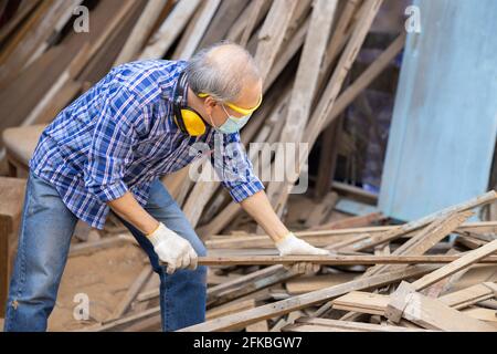 Travailleur aîné bois woodcraft retraite hobby pour la bonne retraite, asiatique homme mature maître professionnel de la fabrication de meubles en bois avec masque protecteur Banque D'Images