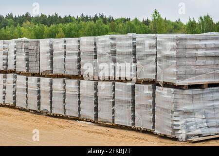 Grand tas de dalles de pierre conditionnées matériau industriel sur palettes sur le chantier. Banque D'Images