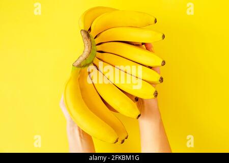 Femme tenant une grande belle main de bananes biologiques mûres juteuses avec beaucoup de doigts. Alimentation végétarienne saine pour le désintoxication printanier de l'été. CLEA Banque D'Images