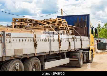 Camion sur le chantier transportant des palettes en bois, du fret industriel ou du fret en bois. Banque D'Images