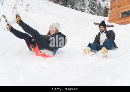 Un jeune couple s'amusant dans le paysage enneigé pendant la saison d'hiver. Porter des vêtements d'hiver en profitant de la promenade en traîneau dans un paysage enneigé avec des arbres enneigés. Banque D'Images