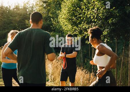 Instructeur de fitness entraînant des athlètes masculins et féminins tout en faisant de l'exercice stationnement Banque D'Images