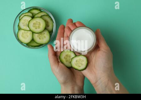 Les mains des femmes tiennent le pot avec des cosmétiques sur fond de menthe avec tranches de concombre Banque D'Images