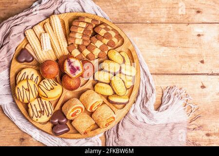 Assortiment de petits gâteaux et muffins. Plaque en bois sur table des anciennes planches, vue du dessus Banque D'Images