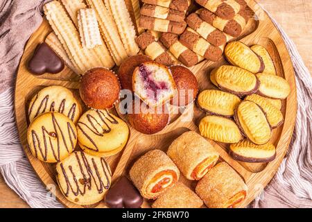 Assortiment de petits gâteaux et muffins. Plaque en bois sur table des anciennes planches, vue du dessus Banque D'Images