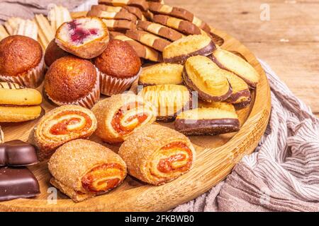Assortiment de petits gâteaux et muffins. Plaque de combinaison en bois sur la table des anciennes planches, gros plan Banque D'Images