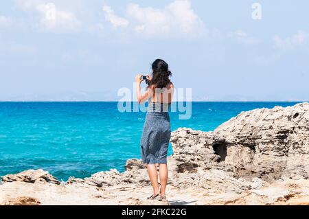 La jeune voyageur prend des photos avec son smartphone de l'horizon au-dessus de la mer en appréciant son voyage d'été à l'île de Formentera, un véritable PA de vacances Banque D'Images