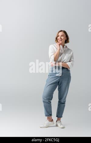 pleine longueur de bonne femme en surpoids en jeans posant dessus gris Banque D'Images