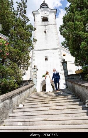 Le Baiser. Mariée et le marié embrasse tendrement sur un escalier en face d'une petite église locale. Banque D'Images
