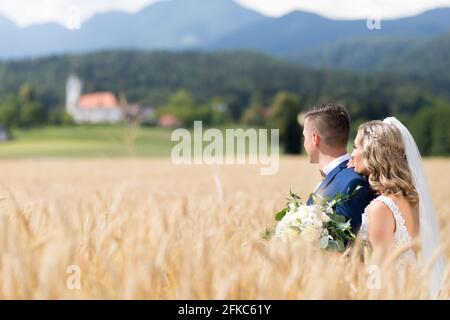 Bride hugs groom tendrement dans champ de blé quelque part dans la campagne slovène. Banque D'Images