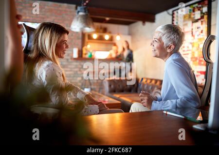 Jeune femme heureuse encadrée par une femme partenaire senior dans le bureau Banque D'Images