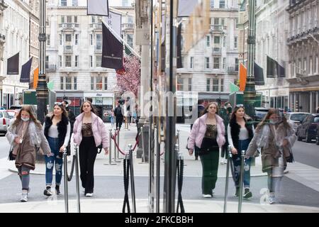Londres, Royaume-Uni, 30 avril 2021 : les visiteurs visitent les boutiques de luxe de Bond Street, comme le reflètent les vitrines du magasin Yves St Laurent. Anna Watson/Alay Live News Banque D'Images