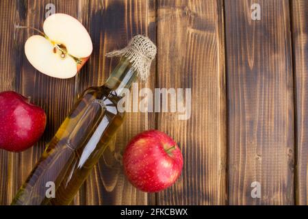 Vinaigre de cidre de pomme dans la bouteille de verre sur fond de bois brun.vue du dessus.espace de copie. Banque D'Images