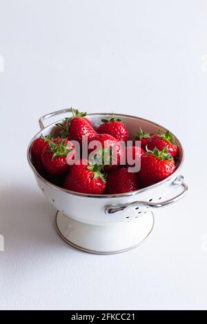 Passoire blanche et argentée remplie de fraises fraîches. Banque D'Images