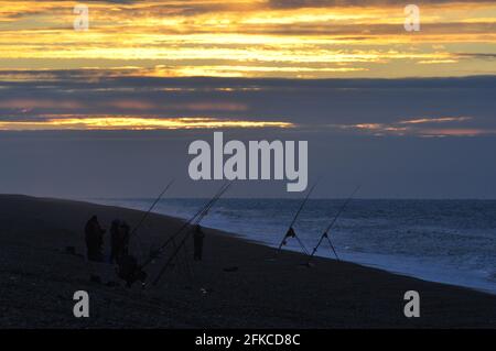 Pêcheurs à la ligne au coucher du soleil sur CLEY-Next-the-Sea Beach au nord de Norfolk, Angleterre, Royaume-Uni Banque D'Images