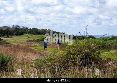 Un couple de randonnée pédestre passe devant les Humps du Diable. Ces barows de l'âge de bronze sont situés à Bow Hill, sur un passage de passage supérieur à Stoughton, dans le parc national de South Downs, à Sussex, au Royaume-Uni Banque D'Images