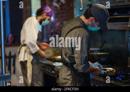 Bellingham, Washington, États-Unis. 29 avril 2021. Le chef de partie Gabe Dean (premier plan, gris) et le sous-chef Nick IULA (arrière-plan, blanc) préparent des repas au populaire restaurant italien Mucca Osteria de Portland, Oregon, le jeudi 29 avril, le dernier jour de repas à l'intérieur avant que la troisième fermeture de la ville ne soit effective. Le gouverneur de l'Oregon, Kate Brown, a déclaré que les restrictions d'une semaine pour les restaurants et les bars étaient en réponse à une augmentation du nombre de nouveaux cas COVID-19. Les repas à emporter et les repas à l'extérieur sont autorisés pour les restaurants capables de les offrir. Credit: Gregg Brekke/ZUMA Wire/Alamy Live News Banque D'Images